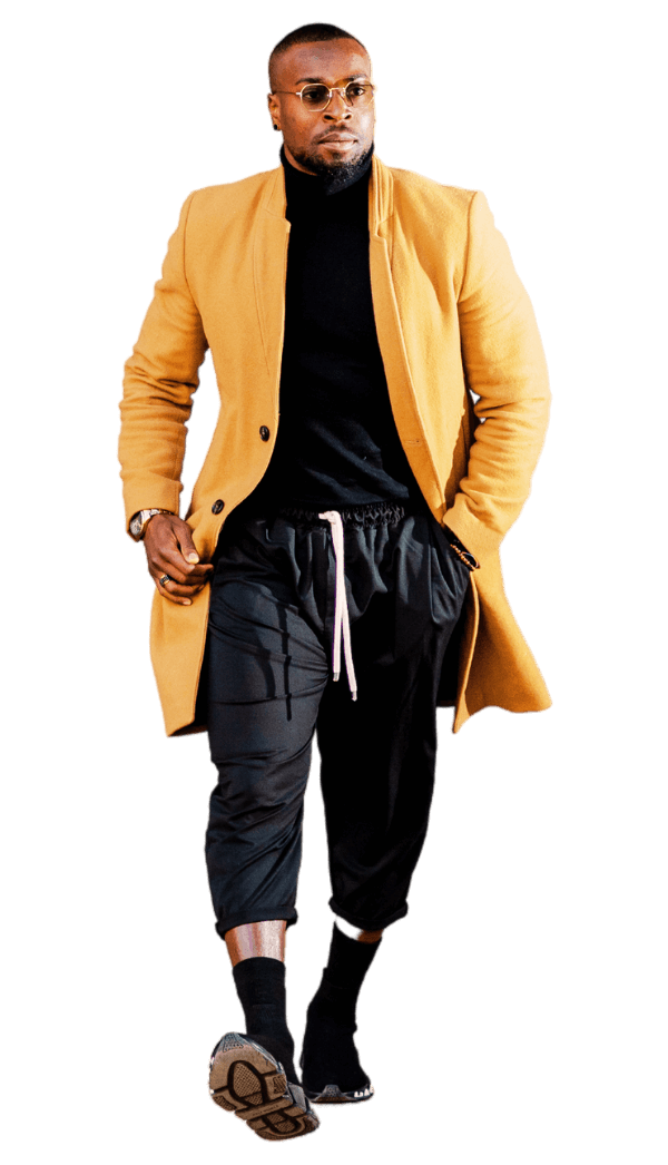 Stylish man in yellow coat with black turtleneck, joggers, and sneakers, exuding the Reality Alchemist™ Framework CONFIDENCE pillar.