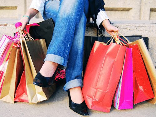 Dr. Madisen Harper shares #myquantumlife, enjoying vibrant retail therapy surrounded by colorful shopping bags and stylish shoes.