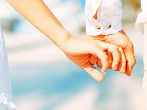 Tender moment of connection, hands holding outdoors, symbolizing love, trust, and intimacy.