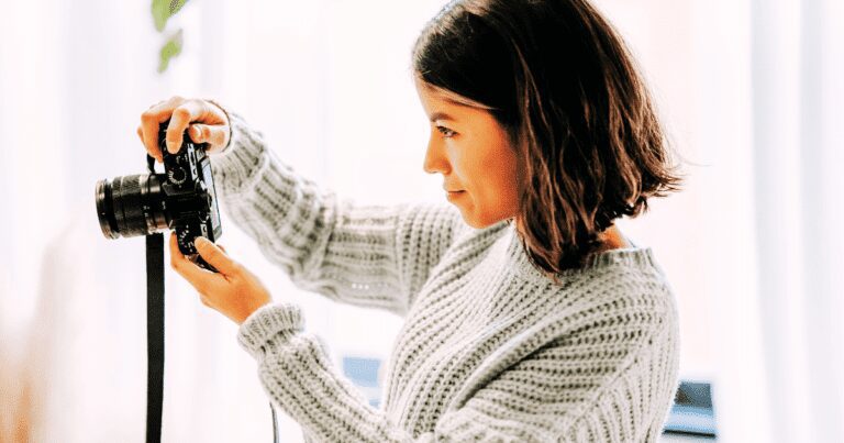 Woman photographing in cozy setting with camera, focused on creative passion.