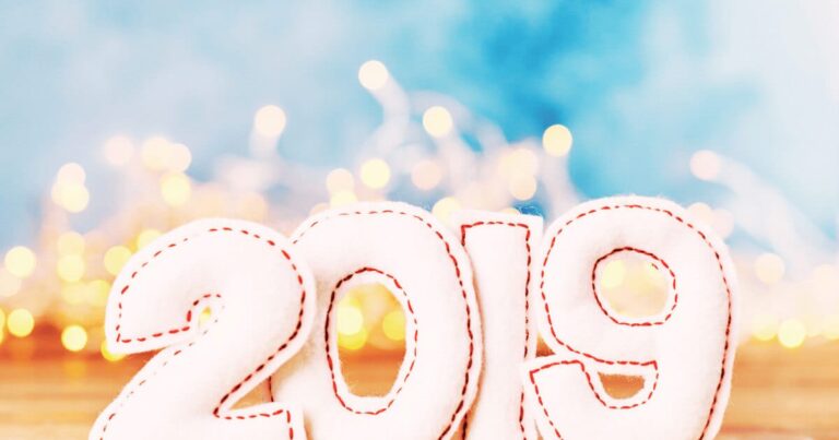 Festive 2019 plush numbers with twinkling lights and serene blue gradient background.