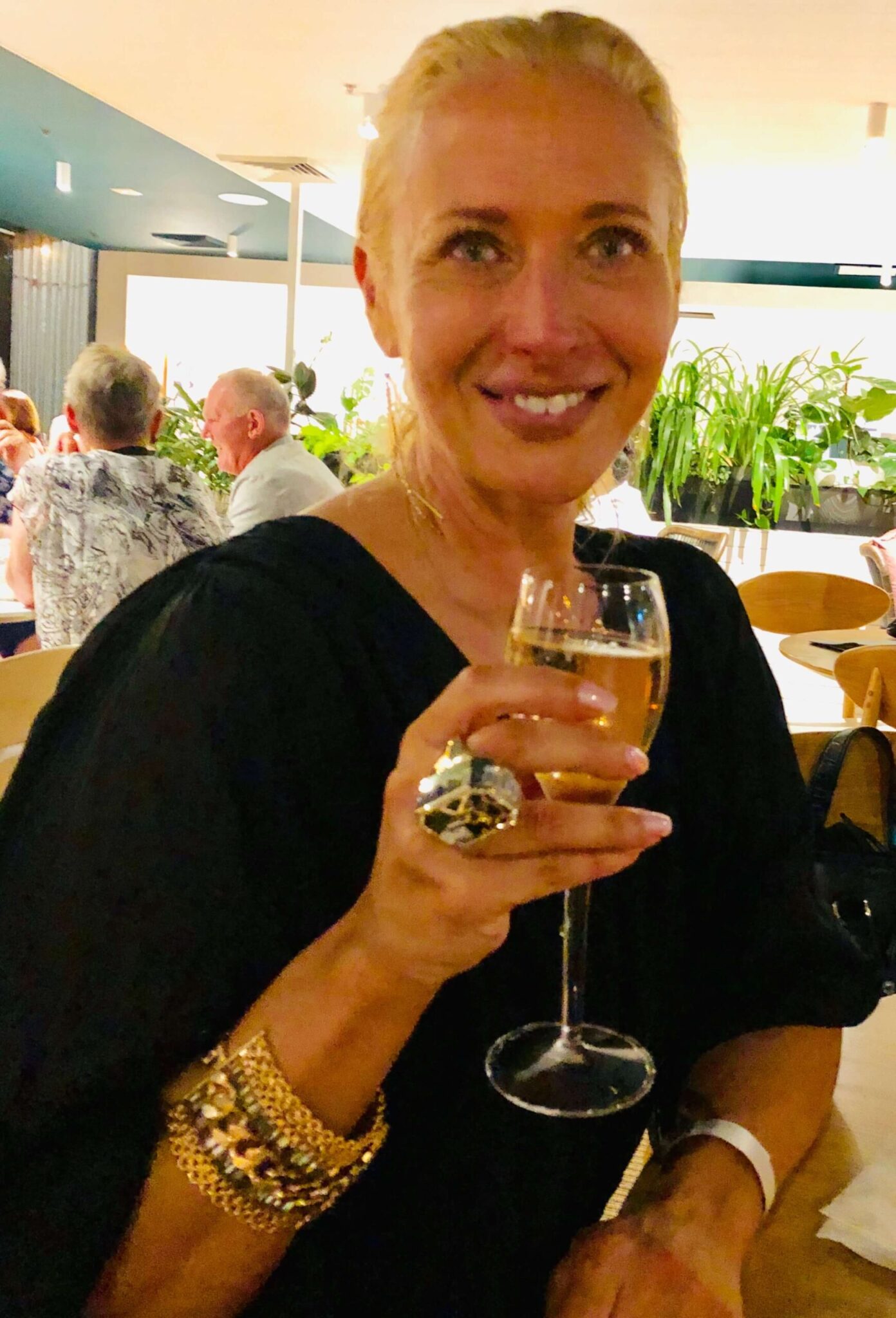 Dr. Madisen Harper, celebrating the New Year, holding champagne, smiling amid joyful ambiance.